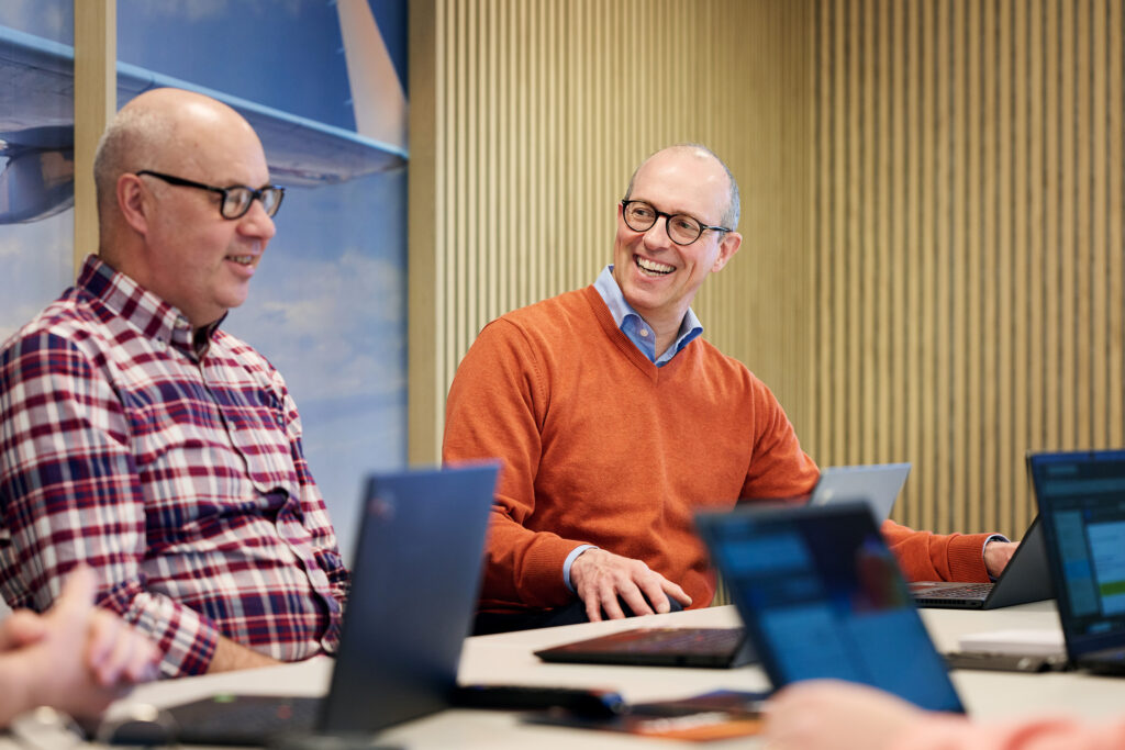 Two men laughing and conversing in a conference room