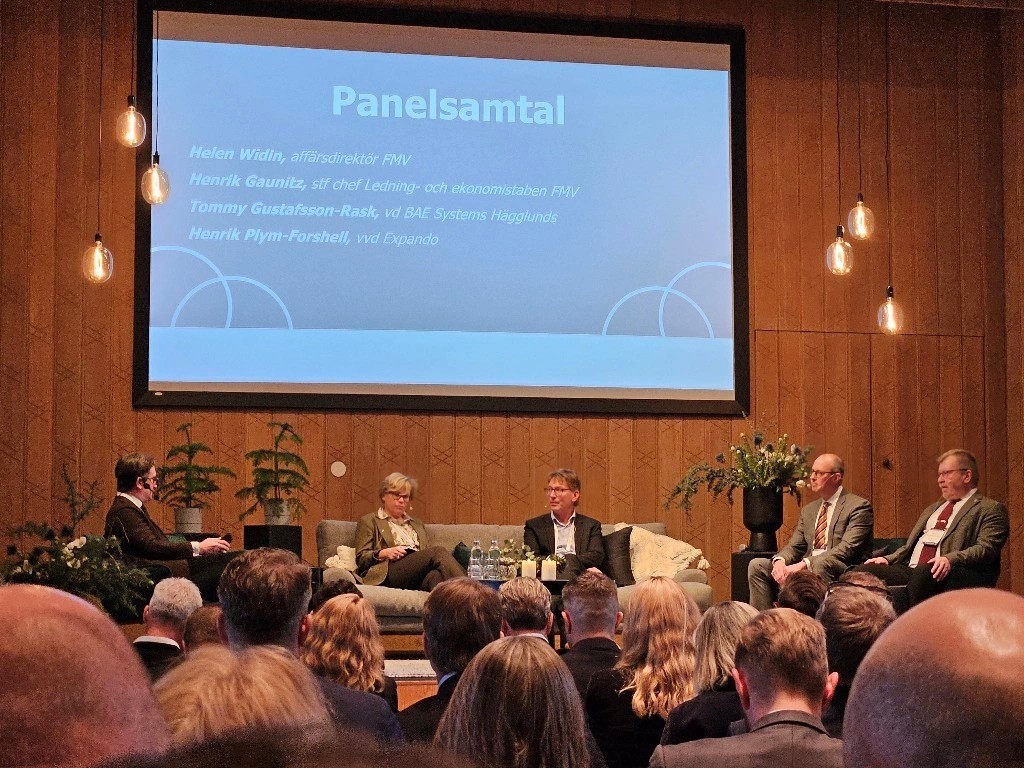 Paneldiscussion on stage in front of a crowd of people